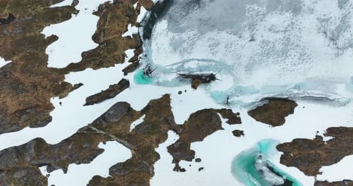 Tundra congelada con vibrantes piscinas de agua de deshielo de color azul entre nieve y terreno rocoso en Noruega