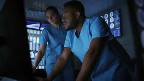 Two Medical Scientists / Neurologists, Talking and Working on a Personal Computer in Modern Labora