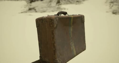 Old Leather Suitcase Resting on a Sandy Surface in an Isolated Area