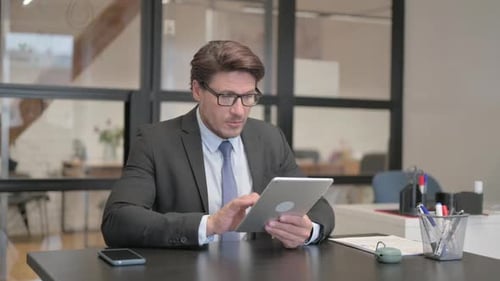 Middle Aged Businessman Using Digital Tablet in Office