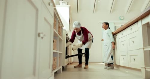 Girl Watches Grandmother Take Tray from Oven