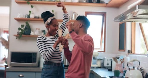 Cheerful Couple Dancing in Kitchen with Wooden Spoons