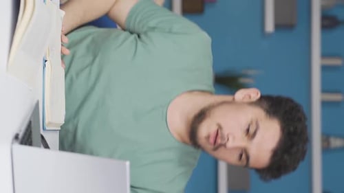 Young Adult Studying At Table with Laptop and Notebook