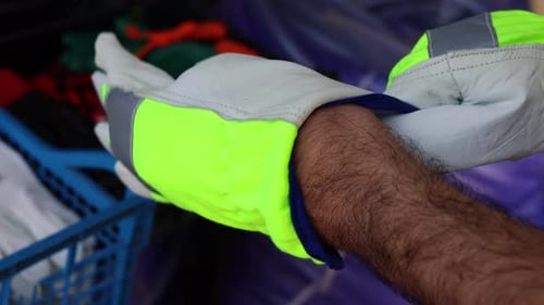 stack of handling gloves for sale outdoor market shop store. man putting hand in working gloves