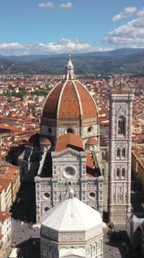 Vertical aerial view of Cathedral of Santa Maria del Fiore zooming out with city and mountains on a