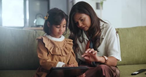Child and Adult Looking at Tablet Together