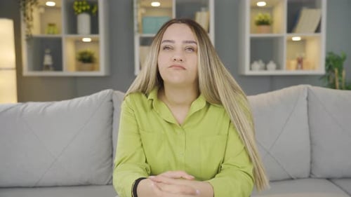 Sad Woman Sits on Couch Looking Down