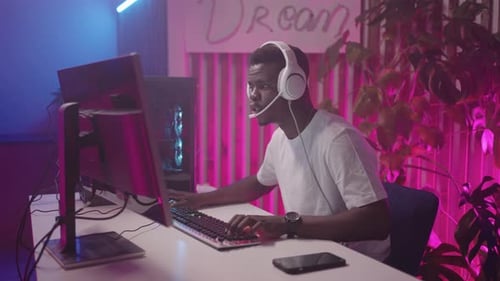 A Young African Man is Happily Engrossed in a Computer Game at the Computer Club Communicating with
