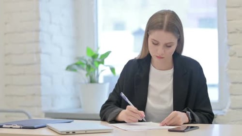 Businesswoman Doing Paperwork while Sitting in Office