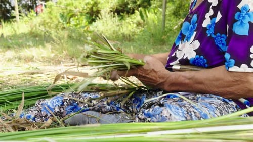 Close up shot of a lady's hands swiftly cutting green raw material to smaller pieces and then drying