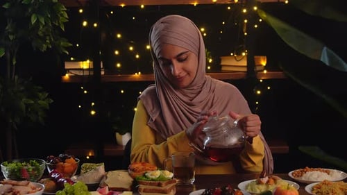 Woman Pours Tea at Festive Meal