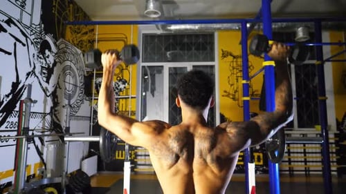 Sporty African Man with Tattoos Lifting Heavy Black Dumbbells at Sport Club Muscular Afro American