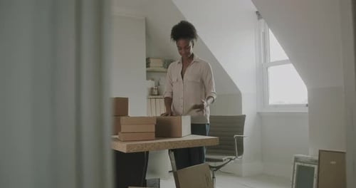 Woman Packs Boxes in Bright Home Office