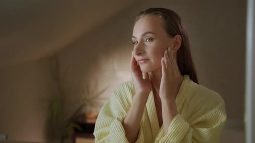 Woman Massaging Face in Mirror with Lotion