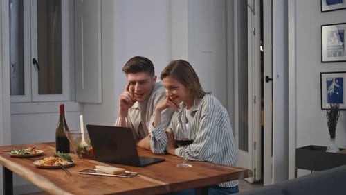Couple Browsing Laptop Together at Dining Table