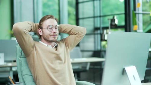 Smiling office worker employee with hands behind head feels satisfied with work well done indoor