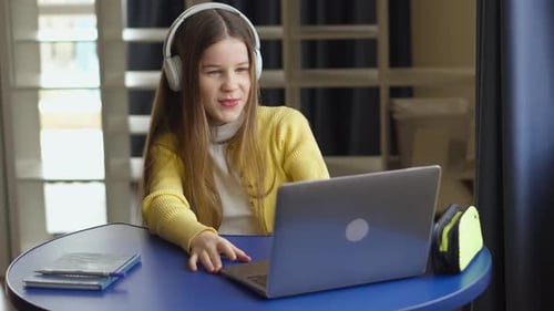 Girl Learns Using Laptop and Headphones Indoors