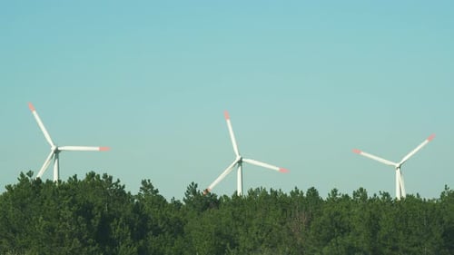Alternative energy sources. Large rotating blades of a wind turbine against a blue sky