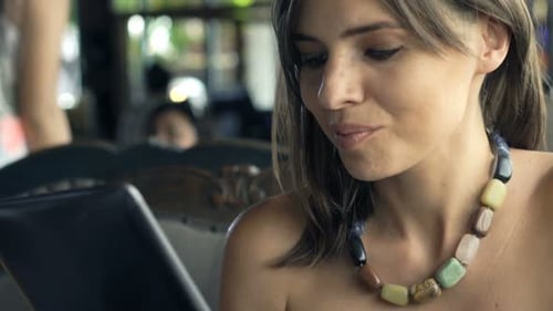 Young Woman Using Tablet Computer Sitting in Cafe 30s