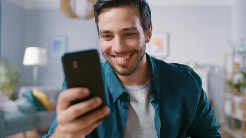 Smiling Man Using Mobile Phone Indoors