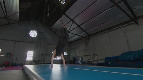 Male Gymnast Performing Sequence of Back Somersaults on Gym Mat