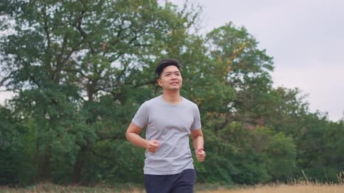 Asian young handsome active sportsman running on street in public park.