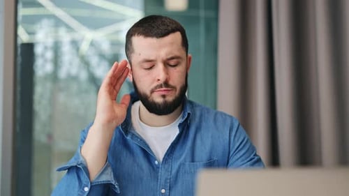 Man Looking at Laptop, Holding His Head