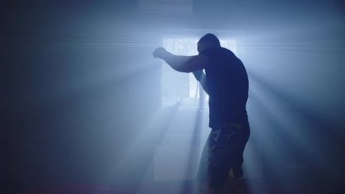 Muscular Man Shadow Boxing in Dark Room
