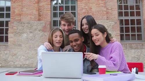 Enthusiastic Friends Gathered Around Laptop on Campus