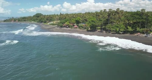 Bali, Indonesia. Aerial View of Ocean Waves Breaks on Black Sand Coast by Green Tropical Landscape a