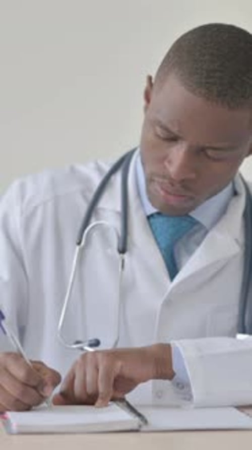 African Doctor Writing Medical Report in Clinic, Vertical Video