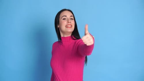 Smiling Woman Gives a Thumbs Up on Blue Background