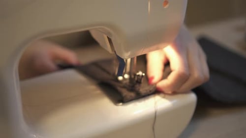 Woman tailor working on sewing machine, hands, close up