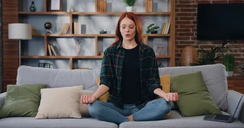 Serene Woman Meditating on Sofa at Home
