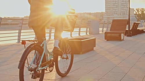 Unrecognizable Woman Cycling Along Bank Of River