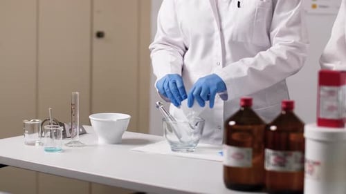 Une crème est mélangée dans un bol en verre. La PTA porte des gants et une blouse blanche