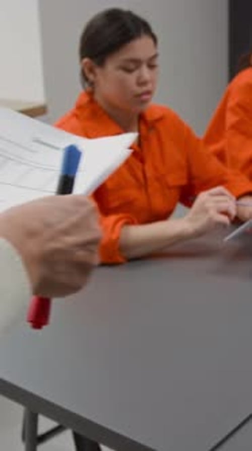 Teacher Giving Test to Students in Orange Jumpsuits