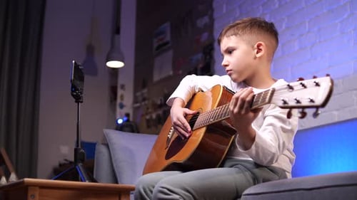 Child Plays Acoustic Guitar at Home