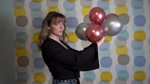Cheerful Woman Holding Red and Silver Balloons