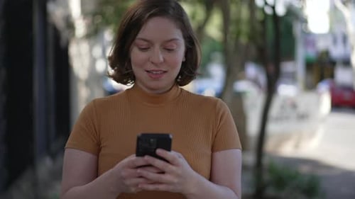 Person reading message notification on phone while walking in street sidewalk