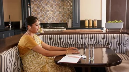 Woman Working on Laptop at Kitchen Table