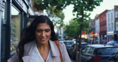 4k video footage of a young woman using a cellphone while walking outside in the city