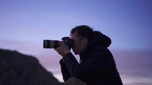 Männlicher Fotograf fotografiert auf einer Berggipfelwanderung bei Sonnenaufgang
