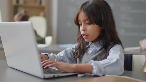 Hispanic Girl Typing on Laptop Keyboard in School