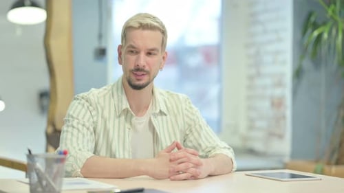 Young Adult Talking at Desk in Office