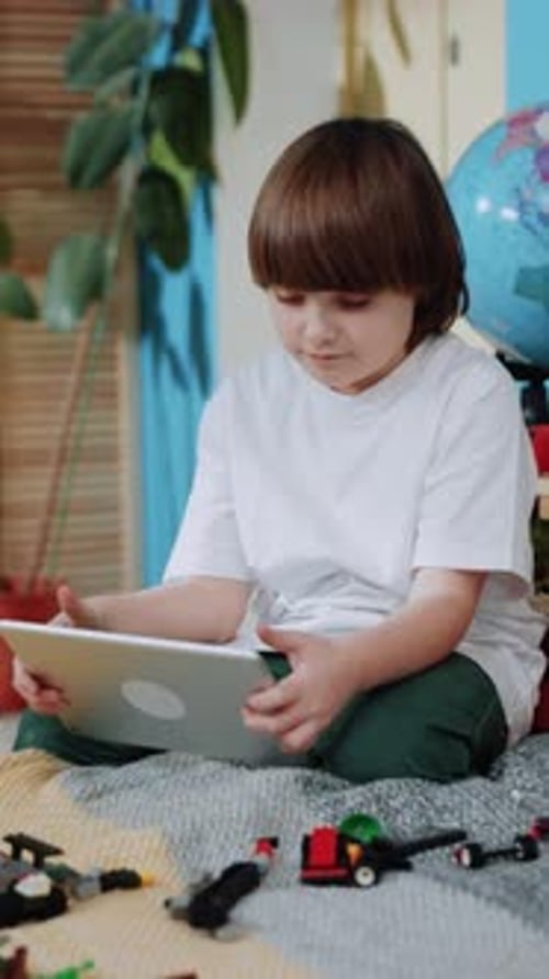 A Child Happily Uses a Colorful Tablet While Sitting Comfortably in a Cozy Indoor Setting