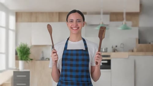 Smiling Young Woman with Cooking Utensils in Kitchen