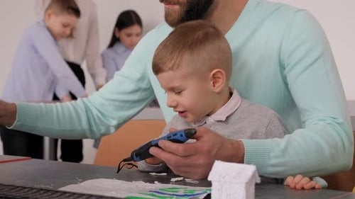 A Father and His Little Son Make a 3d Plastic Model with a 3D Pen in a School