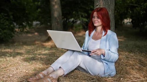 Freelancing Young Businesswoman Working Remotely and Typing on a Computer Keyboard in a Park Sitting
