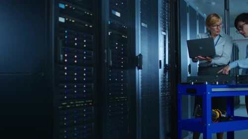 In the Modern Data Center: Female Engineer and Male IT Specialist Work with Server Racks, Discussin